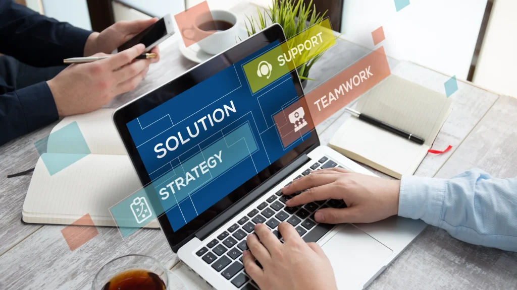 A person working on a laptop with graphical overlays illustrating business solutions, strategy, and teamwork.